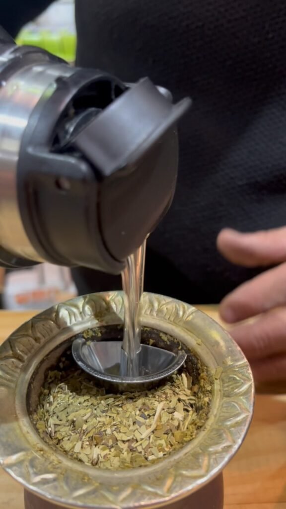 agua de un termo cae sobre un mate con cosito del mate